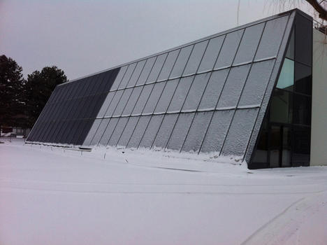La façade du bâtiment Adream un jour de neige, seule une moitié, celle pourvue de panneaux tri-verre, est enneigée.  